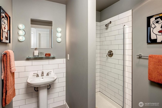 bathroom featuring a sink, a stall shower, and tile walls