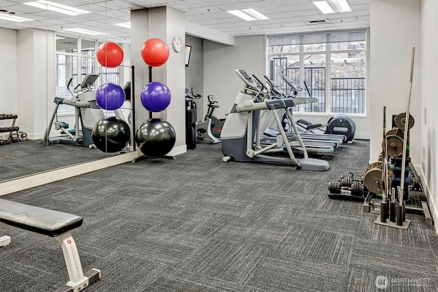 workout area featuring a paneled ceiling and baseboards