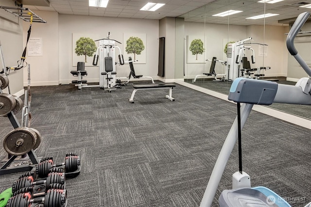 workout area with a paneled ceiling, baseboards, and dark colored carpet