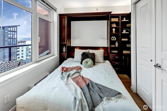 bedroom featuring a closet, baseboard heating, and wood finished floors