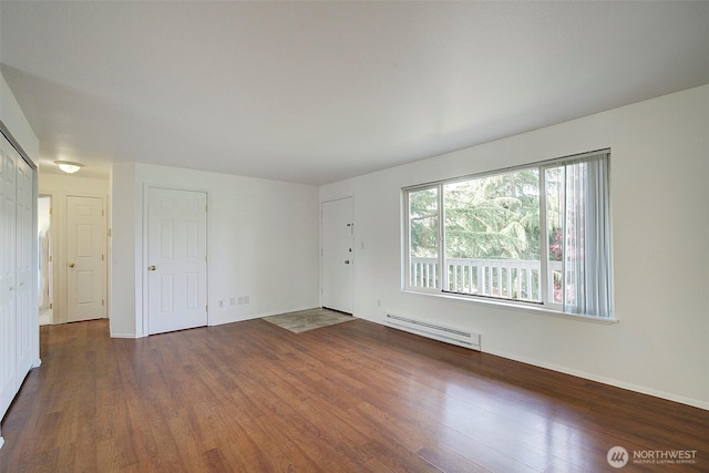 spare room featuring baseboards, baseboard heating, and wood finished floors