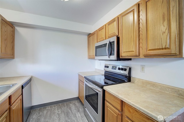 kitchen with stainless steel appliances, light wood-type flooring, light countertops, and baseboards