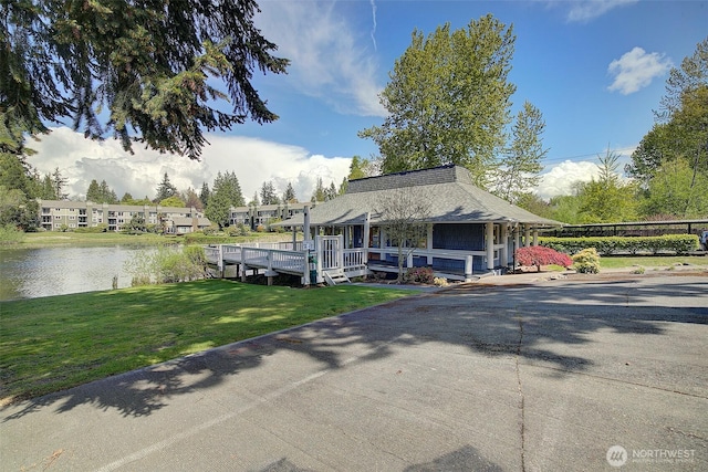 view of front of property with a front lawn, a water view, and a shingled roof