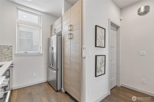 kitchen with backsplash, baseboards, dark wood-type flooring, and freestanding refrigerator