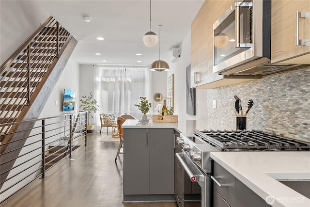 kitchen with tasteful backsplash, gray cabinetry, a peninsula, wood finished floors, and stainless steel appliances