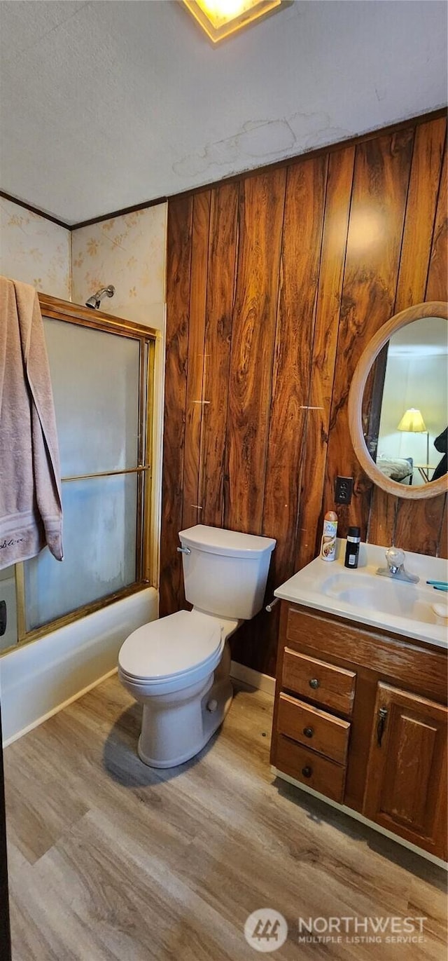 bathroom with combined bath / shower with glass door, vanity, toilet, and wood finished floors