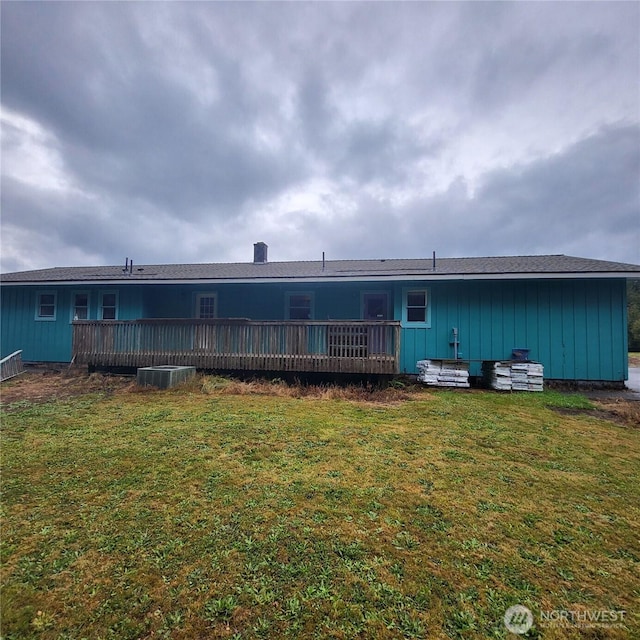 rear view of property featuring a lawn and a deck