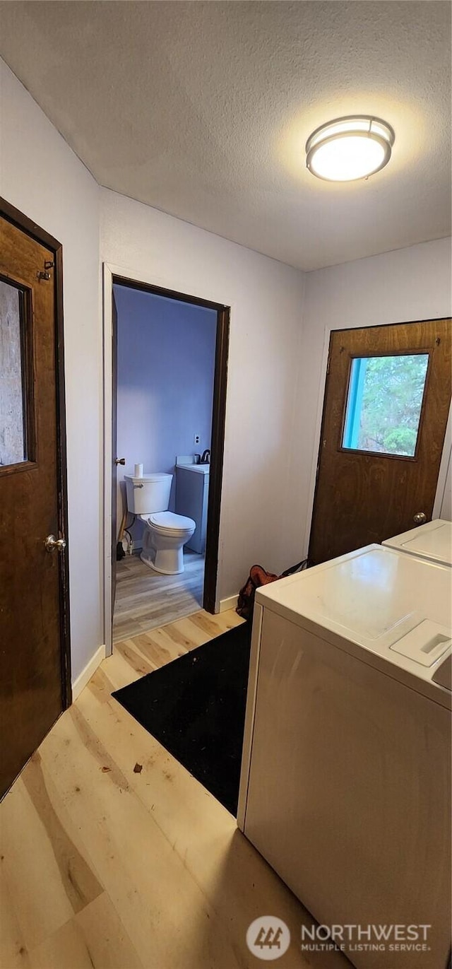 interior space featuring a textured ceiling, wood finished floors, and washing machine and dryer