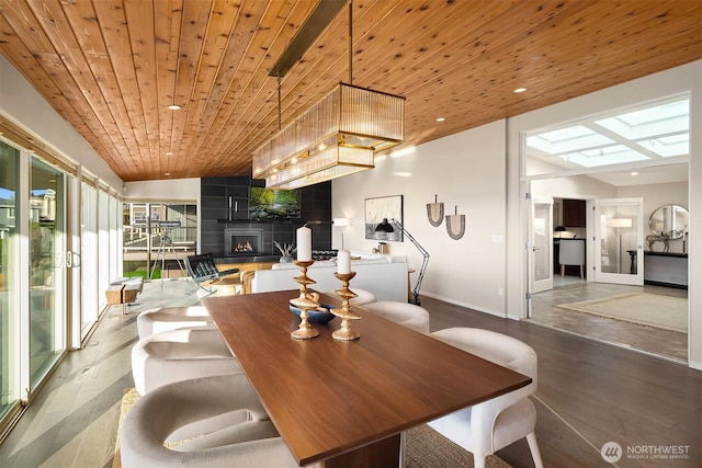 dining room featuring a skylight, recessed lighting, wood ceiling, a large fireplace, and wood finished floors