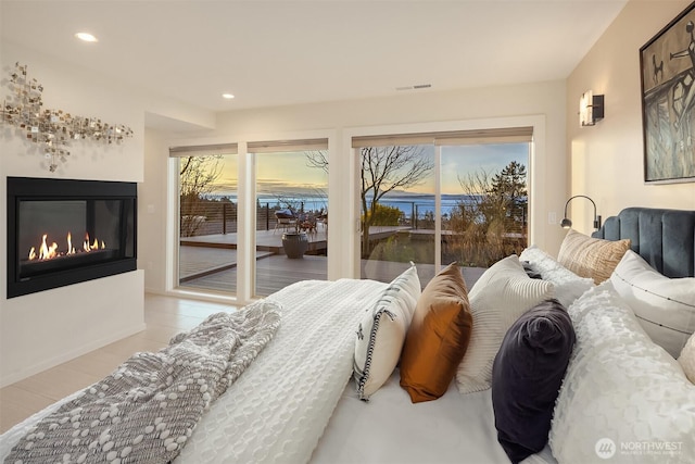 tiled bedroom featuring access to outside, a glass covered fireplace, visible vents, and recessed lighting