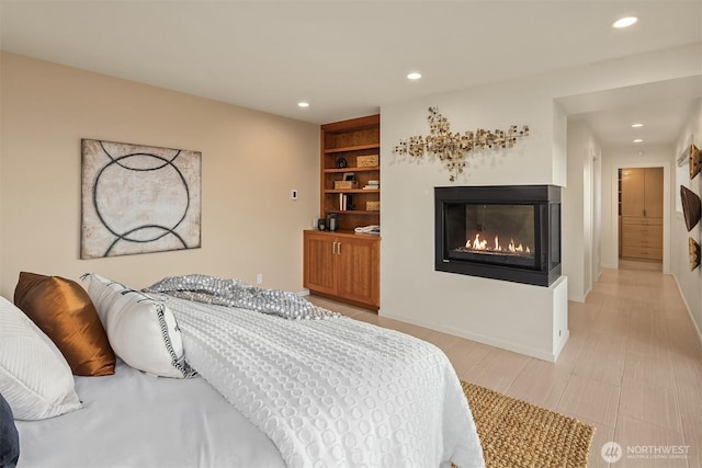 bedroom with a glass covered fireplace and recessed lighting