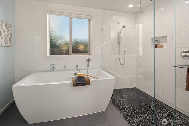 bathroom with a stall shower, tile walls, a freestanding bath, and tile patterned floors