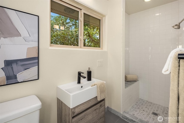 full bath with a sink, a tile shower, and toilet