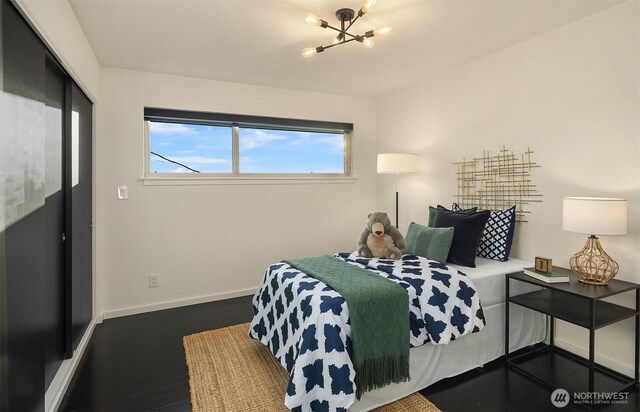 bedroom featuring an inviting chandelier, baseboards, and dark wood-style flooring