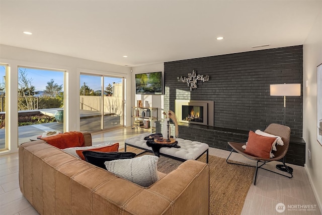 living room with brick wall, a brick fireplace, visible vents, and recessed lighting