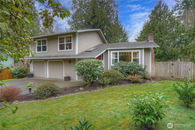 split level home with a garage, a front lawn, a chimney, and fence