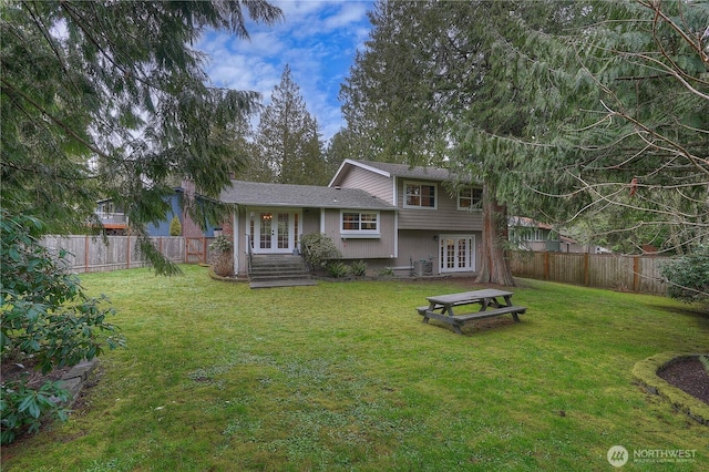 rear view of property with a yard, french doors, and a fenced backyard