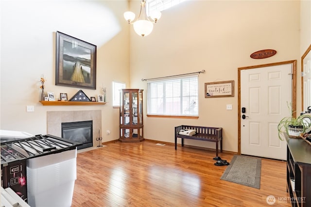 entrance foyer with a tile fireplace, baseboards, light wood-type flooring, and a towering ceiling