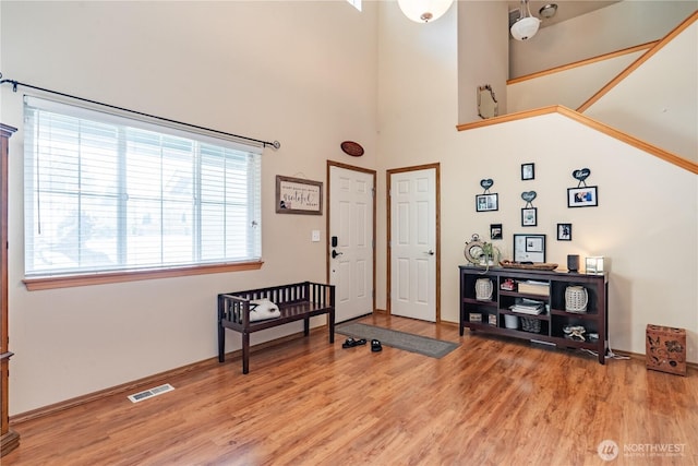 foyer entrance featuring light wood-style floors, visible vents, and a towering ceiling