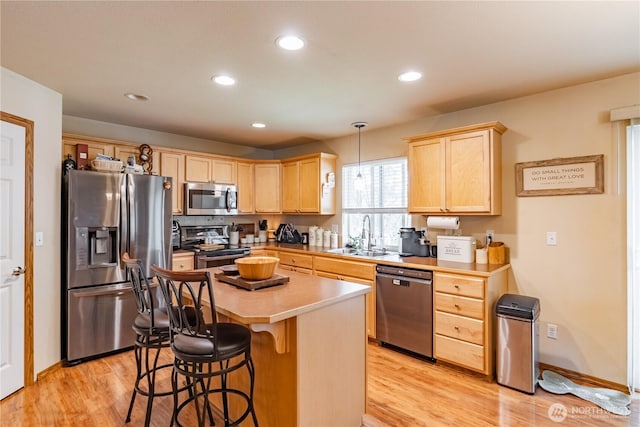 kitchen with light brown cabinetry, light wood finished floors, stainless steel appliances, and a sink