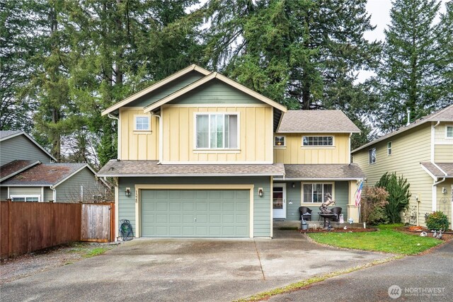 view of front of house featuring board and batten siding, fence, a porch, a garage, and driveway