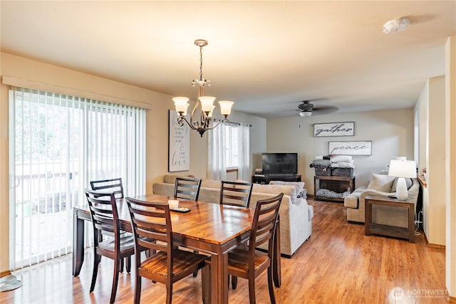 dining room featuring ceiling fan with notable chandelier and light wood-style floors