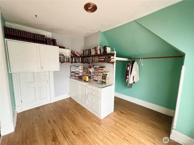 interior space featuring baseboards, light countertops, white cabinetry, and light wood-style floors