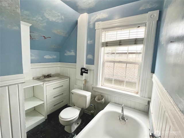 bathroom featuring toilet, a wainscoted wall, a sink, vaulted ceiling, and a bath