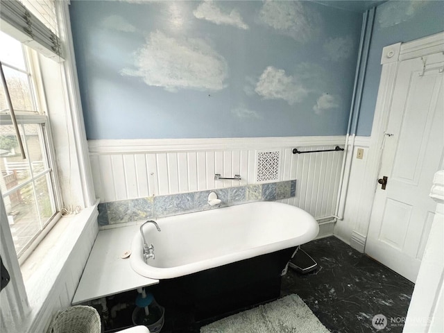 full bathroom featuring marble finish floor, wainscoting, and a freestanding bath