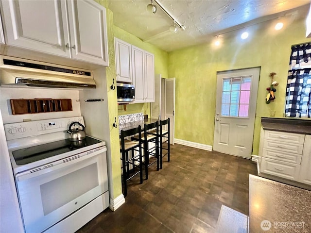 kitchen with under cabinet range hood, white electric range, white cabinetry, stainless steel microwave, and track lighting