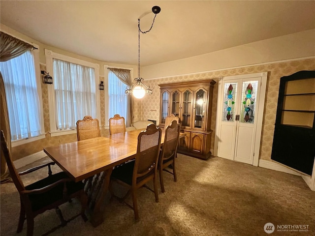 carpeted dining space with wallpapered walls and baseboards