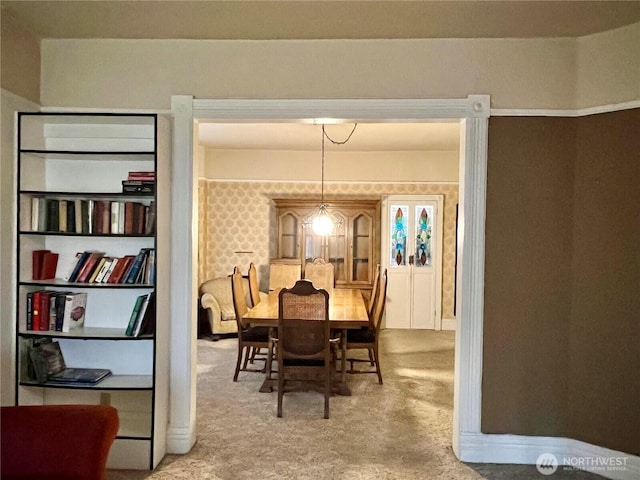 carpeted dining space with baseboards and wallpapered walls