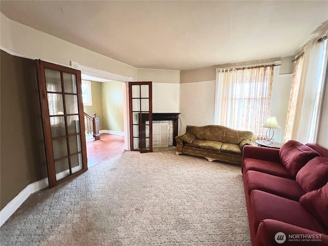 carpeted living area featuring french doors, plenty of natural light, and baseboards