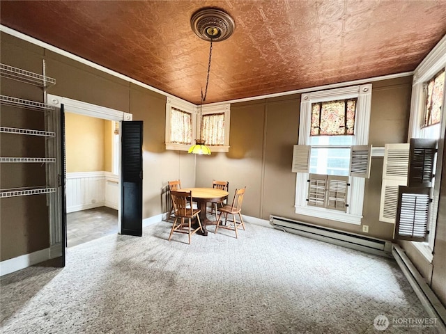 unfurnished dining area with a baseboard heating unit, carpet, an ornate ceiling, and a decorative wall