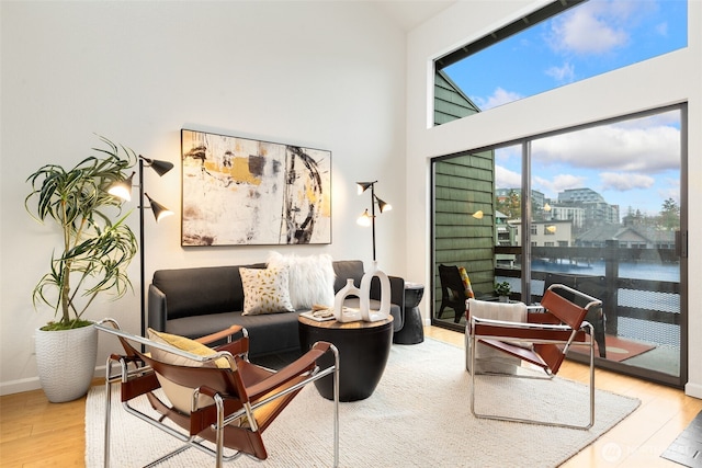 sitting room featuring baseboards, high vaulted ceiling, wood finished floors, and a city view