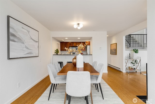 dining space featuring light wood-style floors, baseboards, baseboard heating, and recessed lighting