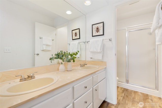 full bathroom with wood finished floors, a stall shower, and a sink