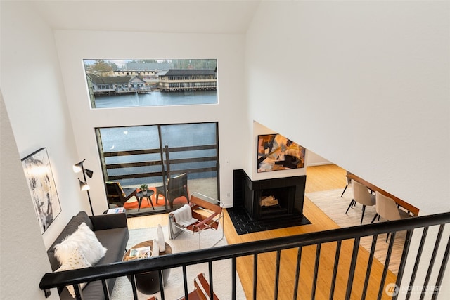 staircase featuring wood finished floors, a towering ceiling, and a multi sided fireplace