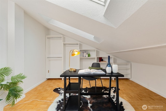 office area featuring vaulted ceiling with skylight and baseboards