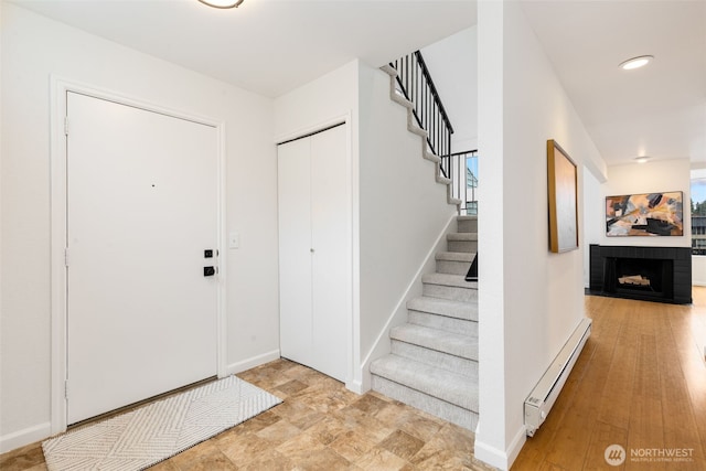 entryway with recessed lighting, a baseboard heating unit, baseboards, stairs, and a brick fireplace