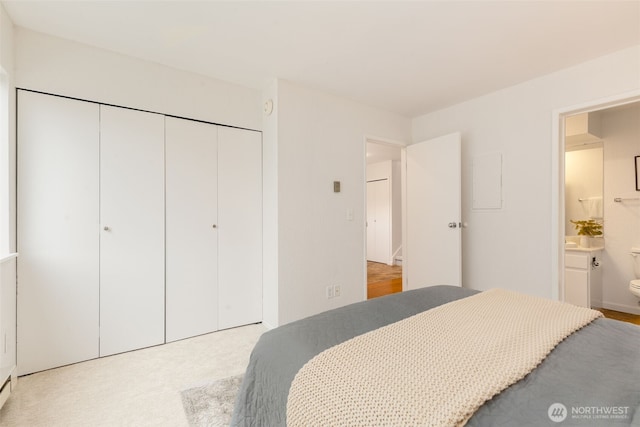 bedroom featuring a closet, light colored carpet, and connected bathroom