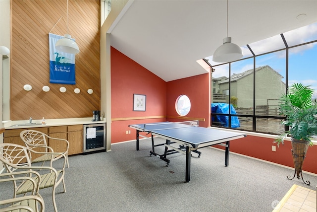 playroom featuring wine cooler, carpet flooring, a sink, wood walls, and high vaulted ceiling