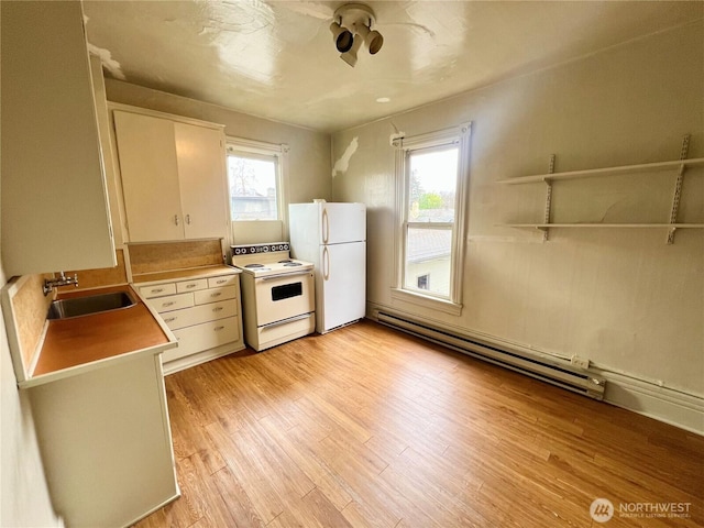 kitchen with white appliances, baseboard heating, a healthy amount of sunlight, light wood-style floors, and a sink