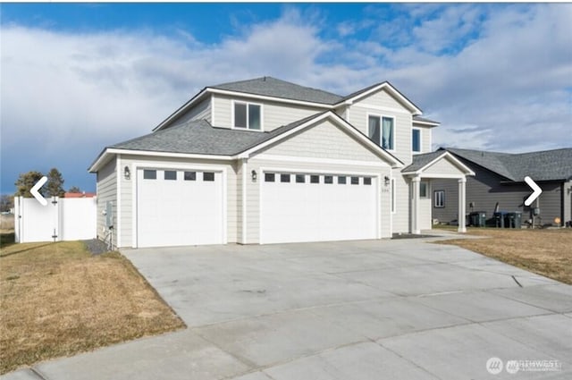 traditional home featuring driveway, a front lawn, an attached garage, and fence