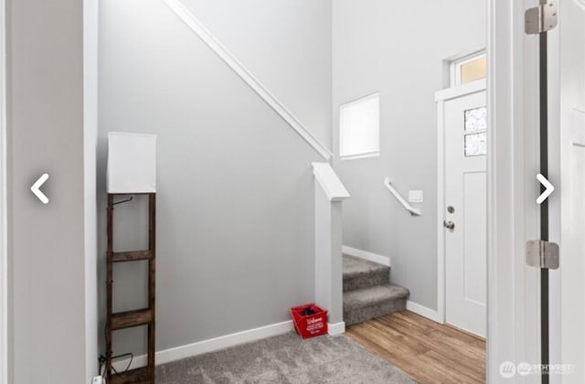 carpeted entryway featuring stairway and baseboards