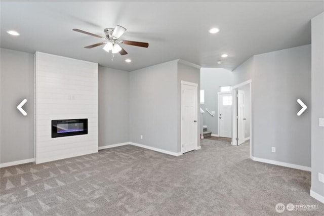 unfurnished living room with a large fireplace, baseboards, carpet flooring, and recessed lighting