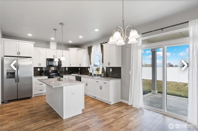 kitchen featuring decorative backsplash, wood finished floors, a center island, black appliances, and white cabinetry