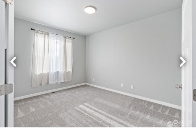 spare room featuring carpet and baseboards