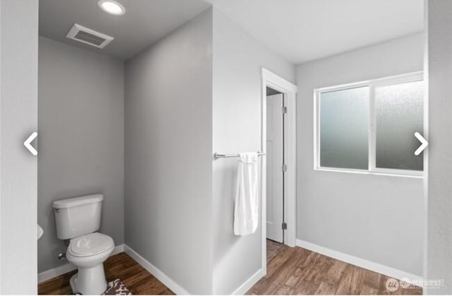 bathroom featuring baseboards, visible vents, toilet, and wood finished floors