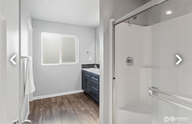 bathroom with a stall shower, baseboards, wood finished floors, and vanity